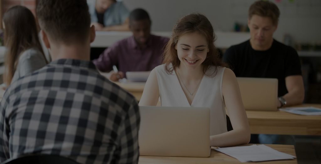 Young smiling woman working on laptop in coworking office space